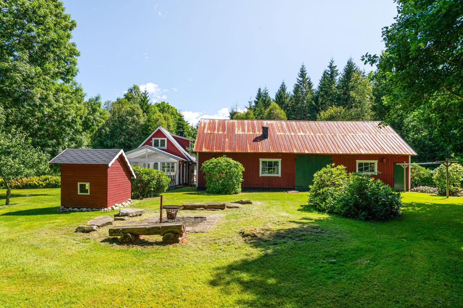 Trädgården med grillplats, lekstuga och lada
